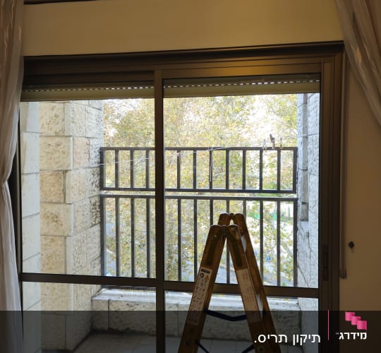 סולם וכלים ליד חלון עם תריסים